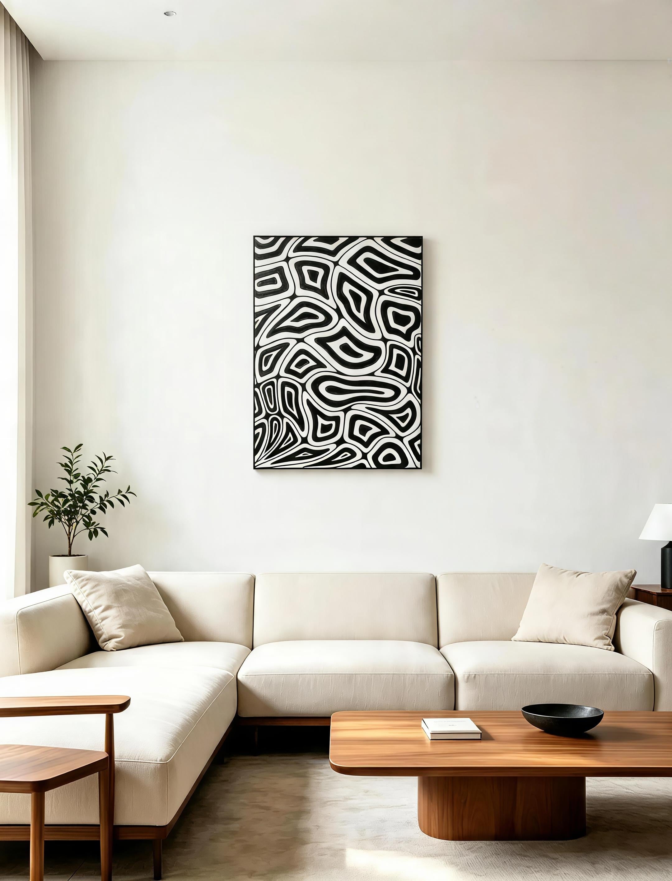Black and white abstract organic pattern art print in black frame displayed in minimalist white living room above cream sectional sofa